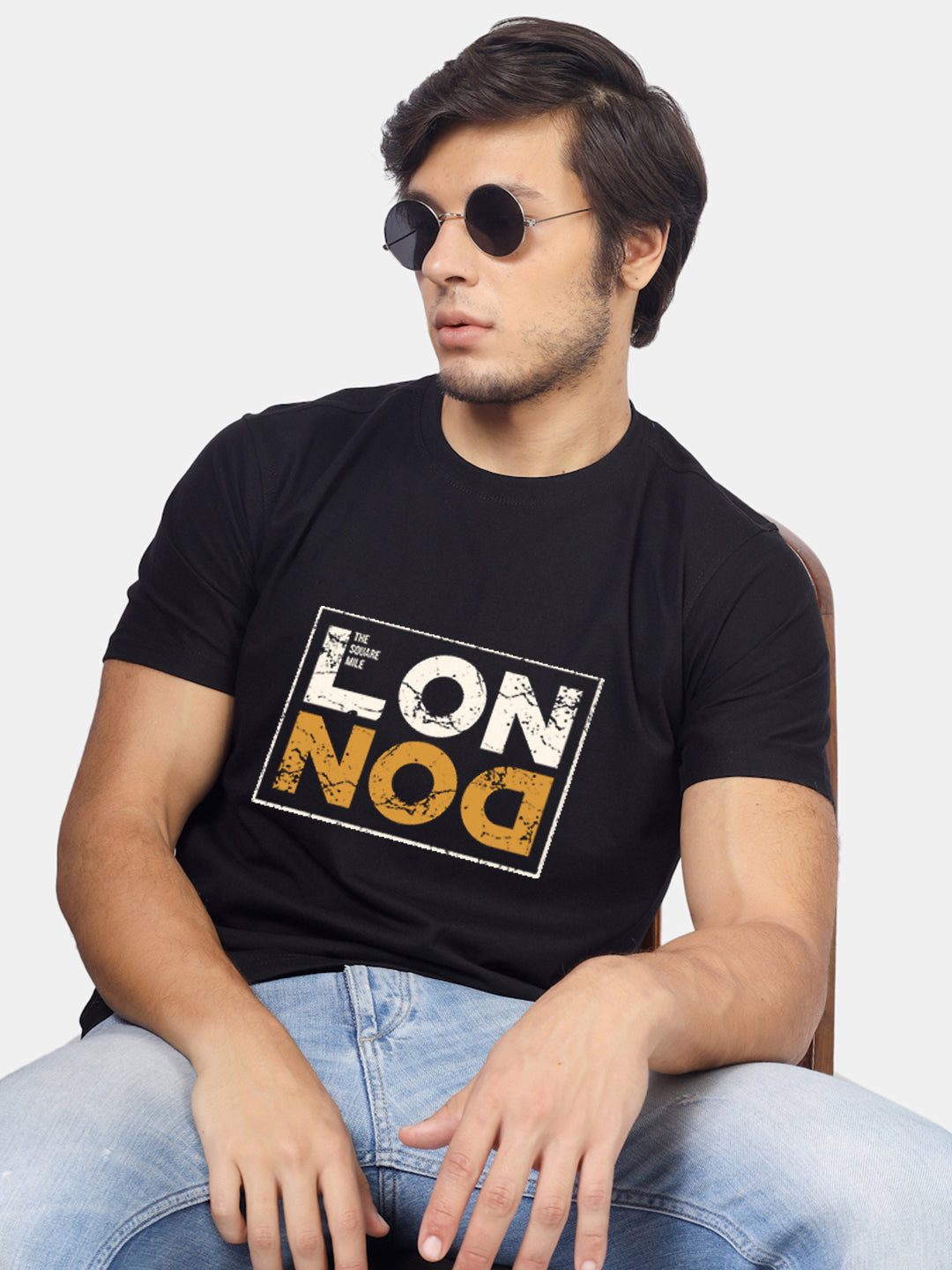 Man in round sunglasses wearing a black T-shirt with a bold London print
