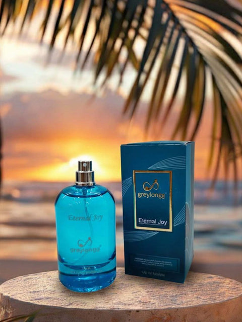 Greylongg Eternal Joy eau de parfum bottle and box on a beach at sunset